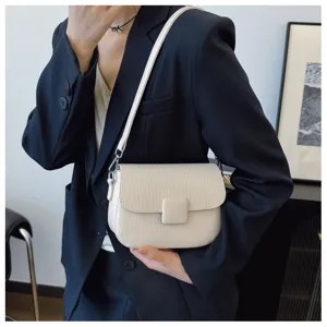 Model wearing a beige textured retro flap crossbody bag with navy blazer