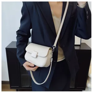 Close-up detail of cream retro flip crossbody bag styled with navy blazer for women