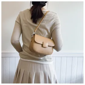 Rear view of a model wearing a tan vintage flap crossbody bag with square buckle
