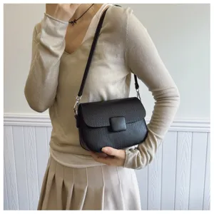 Detail view of a black retro flip shoulder bag worn by a model in a beige outfit.