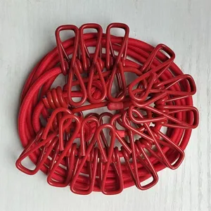 Close-up of portable elastic clothesline with red clips neatly coiled on the surface