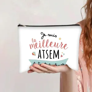 Hand holding a white canvas zipper pouch featuring French 'Meilleure ATSEM' text print