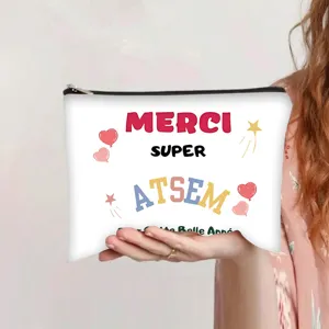 Detail view of a white canvas makeup bag held by hand featuring Merci Super Atsem print