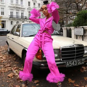 Pink satin two-piece outfit featuring chic blazer top and trousers with playful feather cuffs.