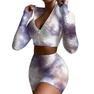 Tie-dye workout two-piece set featuring long sleeve zip crop top and matching fitness shorts.