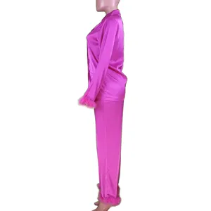 Side detail of bright pink satin pajama set with feather cuffs and smooth fabric texture.