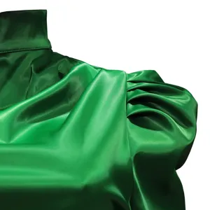 Green satin blouse detail featuring high collar and elegant gathered puff shoulders.