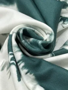 Close-up detail of dark green and white tie-dye fabric texture, soft and smooth material.