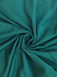 Green fabric texture detail shot, showing soft draped swirl pattern of the jumpsuit material.