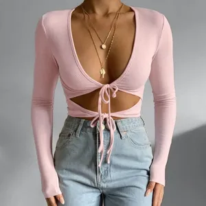 Stylish pink ribbed long sleeve deep v-neck crop top featuring front tie cutout detail.