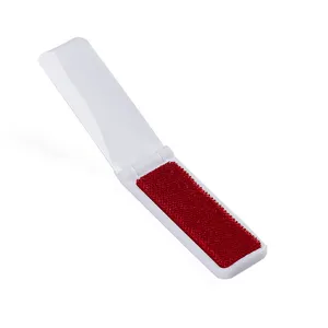Spazzola levapelucchi pieghevole portatile con tessuto in velluto rosso e guscio in plastica bianca.