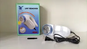 Electric fabric shaver detail showing lint remover with box, power cord and small cleaning brush.