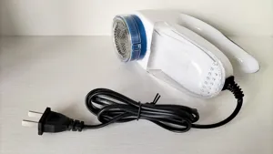 Detailed view of the electric fabric lint shaver with power cord and transparent container.