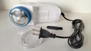 Electric fabric lint remover with power cord brush and protective cover for clothes care.
