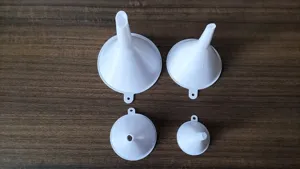 Detail view of four-piece white plastic funnel set with hanging hole for home kitchen use.