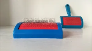 Blue and red pet slicker brush with stainless steel pins for grooming cat and dog fur coats.