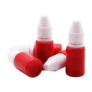 Refill ink bottles, red plastic squeeze bottles with white nozzle caps for office stamps.