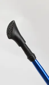 Close-up detail of the ergonomic black rubber handle and blue aluminum trekking pole.
