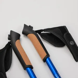 Aluminum alloy trekking pole detail, ergonomic cork handle and adjustable strap for outdoor hiking.