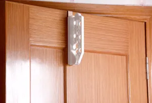 Detail view of a white plastic folding clothes hanger with 5 holes, hanging on a door.