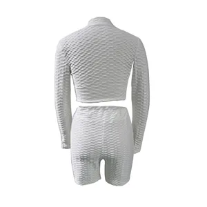 Details of the white textured long sleeve crop top and biker shorts activewear set style.