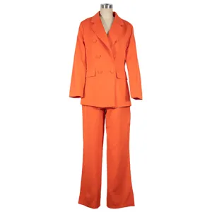 Dettaglio abito da donna arancione con blazer doppiopetto ed eleganti pantaloni larghi.