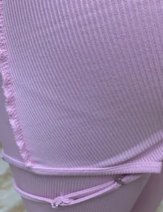 Close up view of pink ribbed fabric texture, showing fine knit details and strap work.