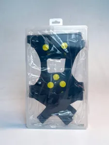 Outdoor non-slip crampons with yellow studs in clear box for winter snow hiking safety.