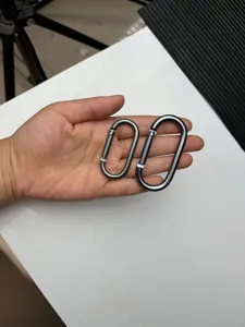 Detailed view of gunmetal oval aluminum alloy carabiner snap hooks held in hand clearly.