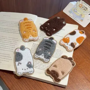 Detailed view of multiple cute cartoon cat hair patches arranged on an open vintage book
