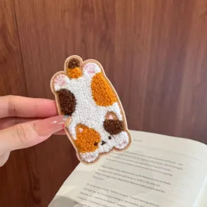 Detail shot of a cute plush calico cat hair patch for bangs with embroidered textures