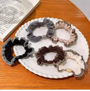 Détail de cinq chouchous élastiques à carreaux sur une assiette décorative.