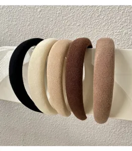 Detailed view of five padded French-style headbands in neutral colors on display stand