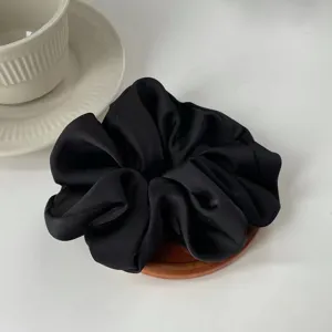Macro view of black oversized satin scrunchie with silky smooth texture