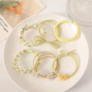 Collection of six elegant pale yellow elastic hair ties with floral and bow decorations