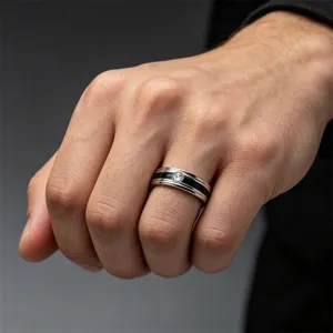 Dettaglio anello di coppia in acciaio inox con scanalatura nera e pietra centrale.