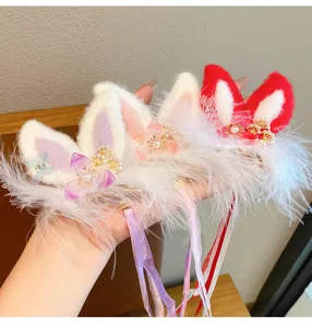 Close-up detailed view of cute plush rabbit ear hair clips with feather trim and tassels