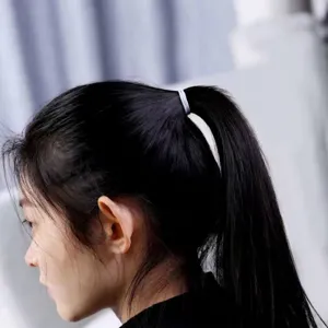 Close-up of white seamless thin hair tie used for a high ponytail on black hair