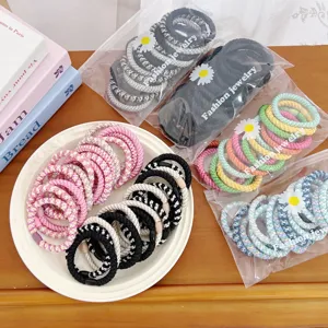 Detail of high elasticity braided hair ties in colorful packaging and a white plate