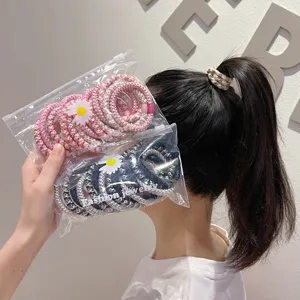 Detail view of colorful braided hair ties in packaging and worn in a ponytail.