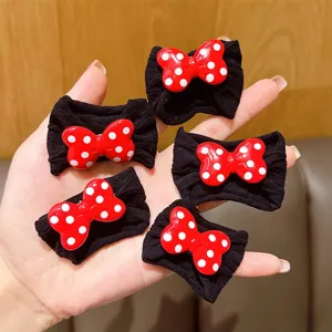 Cinco lindos elásticos para el cabello con lazos rojos y puntos blancos para niñas en mano.