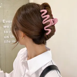 Close-up of a pink wavy hair claw clip styled in a sleek bun on brown hair.