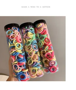 Close-up of three transparent tubes filled with vibrant colorful elastic hair ties for girls