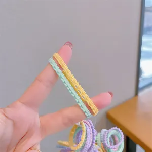 Close-up of macaron colored scalloped elastic hair bands stretched on fingers.