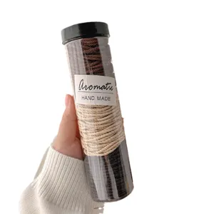 Hand holding clear tube bottle filled with brown and cream braided elastic hair ties