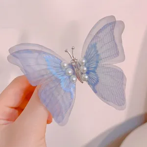 Close-up detail of a light blue mesh butterfly hair clip with white faux pearls decoration