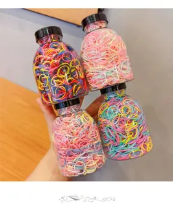 Detailed view of four clear jars filled with colorful elastic hair bands for kids.