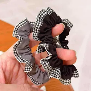Détail de chouchous rétro élégants à carreaux et volantes en tissus gris et noirs hautement élastiques
