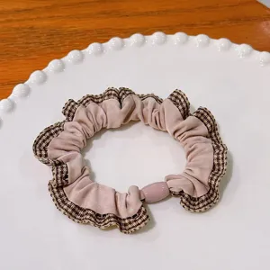 Détail macro d'un chouchou rétro à carreaux avec tissu rose et perle élastique rose.