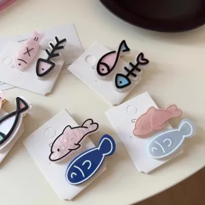 Detail view of cute cartoon fish and fishbone hair clips on white display cards